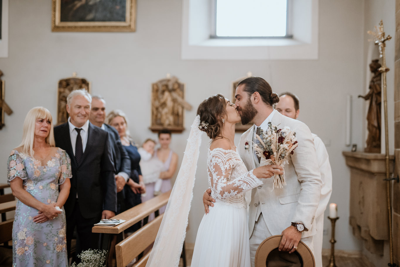 Bräutigam küsst die Braut am Altar vor den Gästen