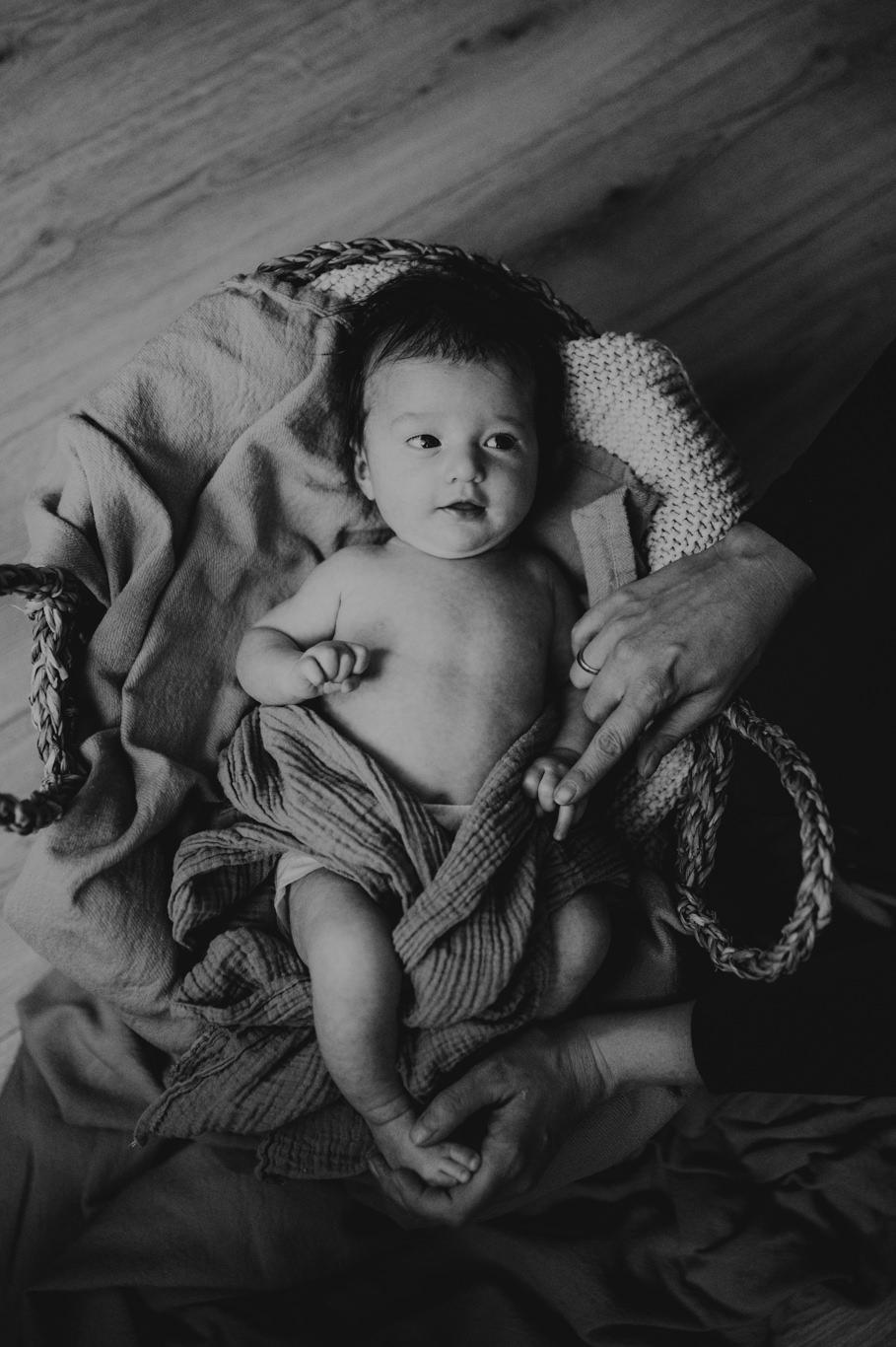 Baby liegt in weiches Tuch gewickelt im Korb, Schwarzweißaufnahme