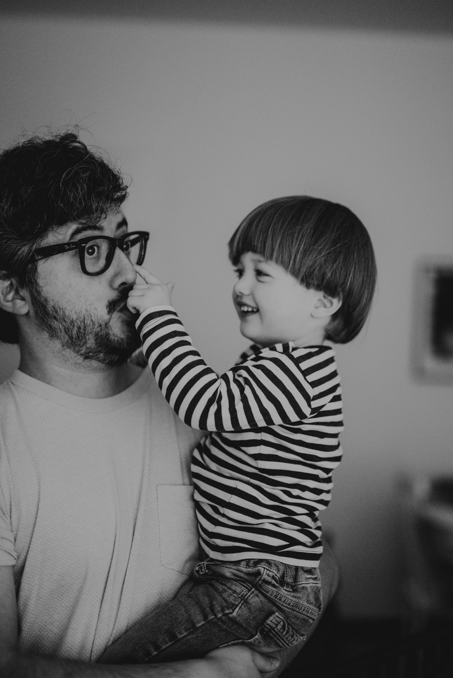 Vater und Kleinkind berühren sich lachend an der Nase, Schwarzweißaufnahme