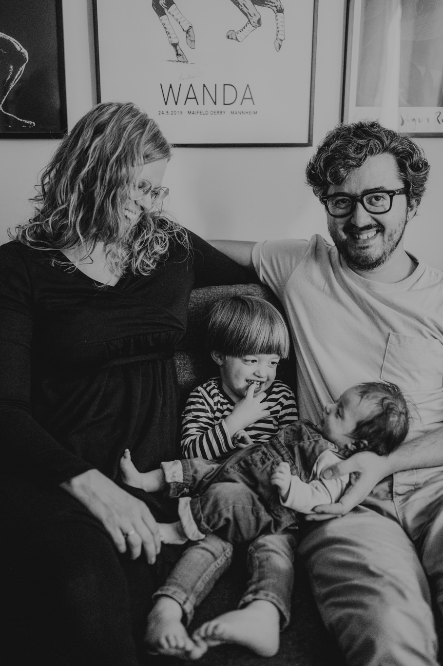 Schwarzweißaufnahme der Familie mit Sohn und Neugeborenem auf dem Sofa
