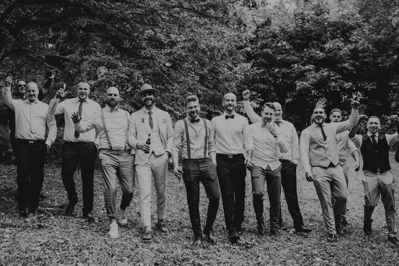 Gruppe Männer im Anzug läuft lachend über die Wiese, Schwarzweißaufnahme
