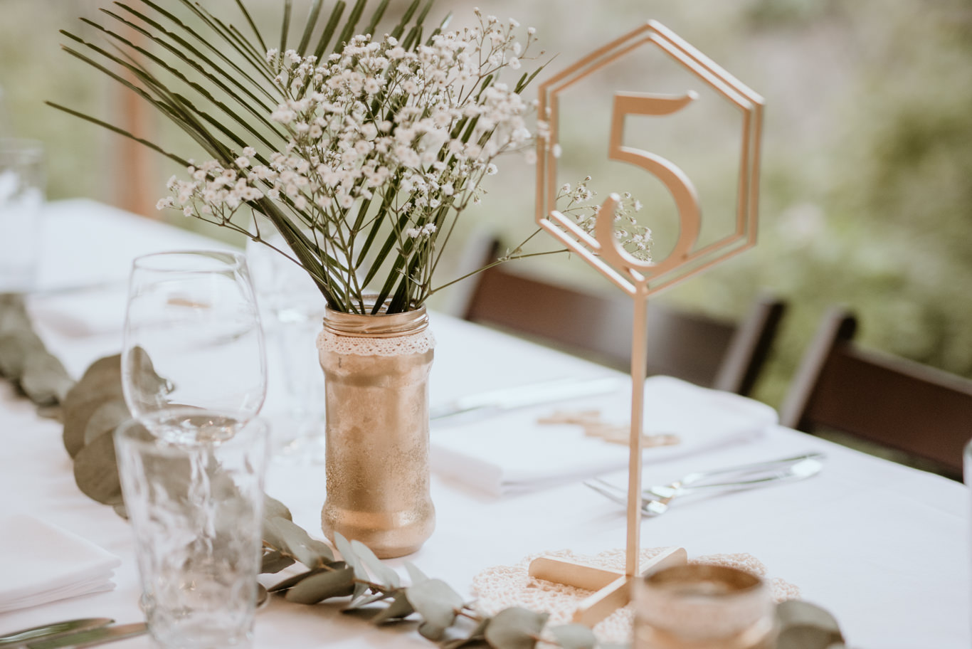 Tischdekoration mit Tischnummer und Palmwedel in goldener Vase