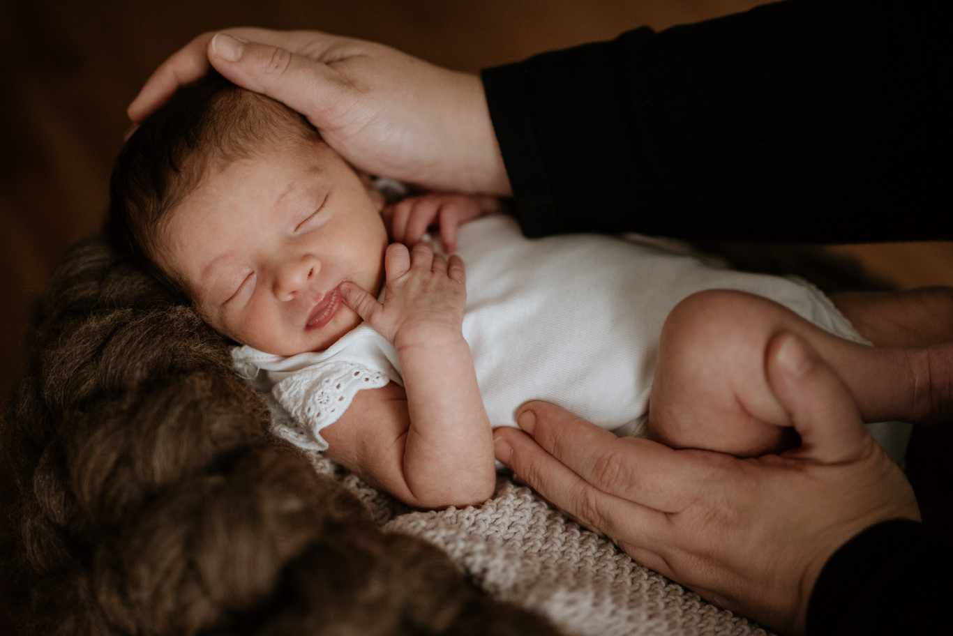 Vater hält sein schlafendes Neugeborenes sanft am Kopf