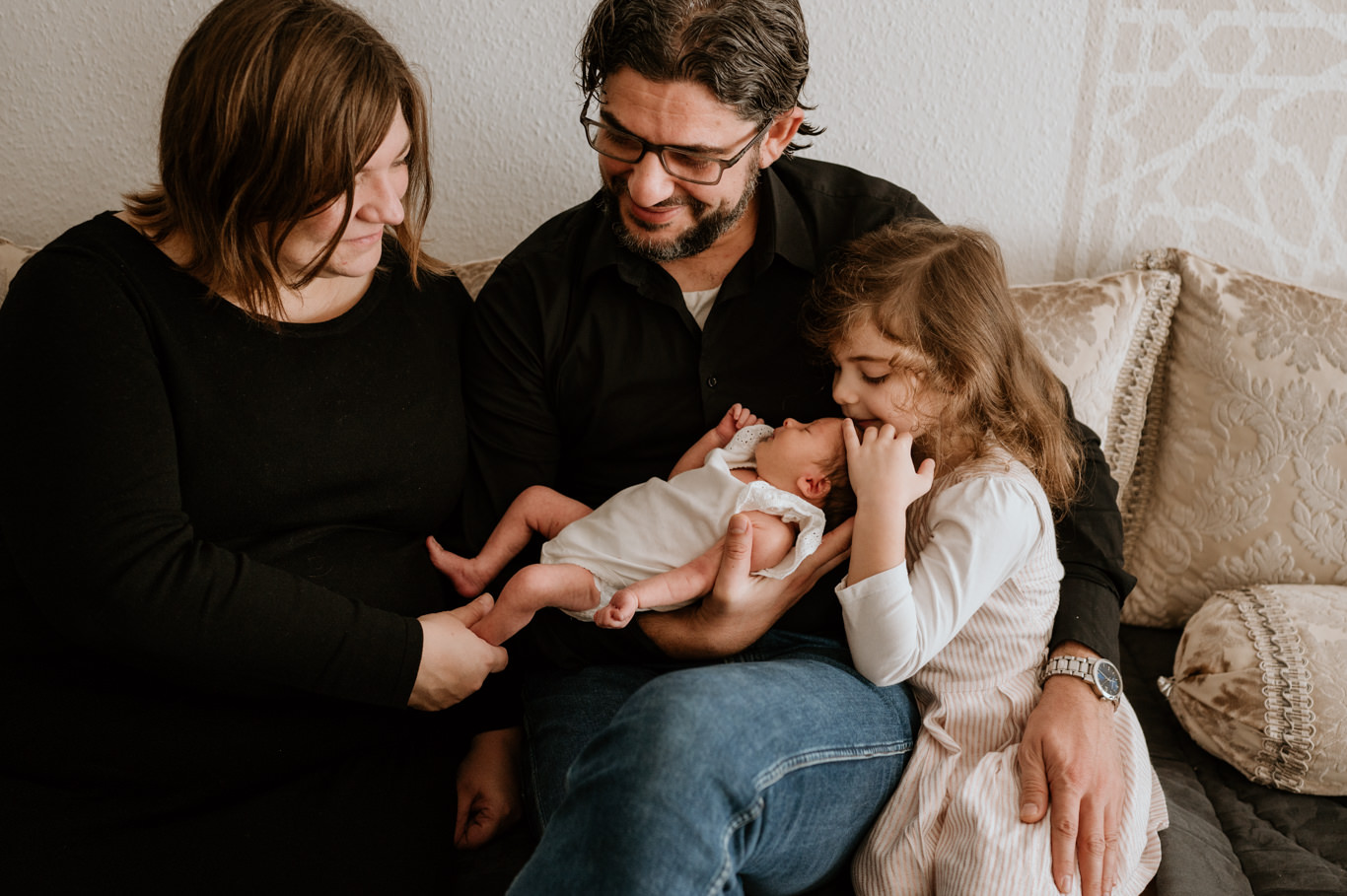 Eltern und Tochter schauen lächelnd auf das neue Baby
