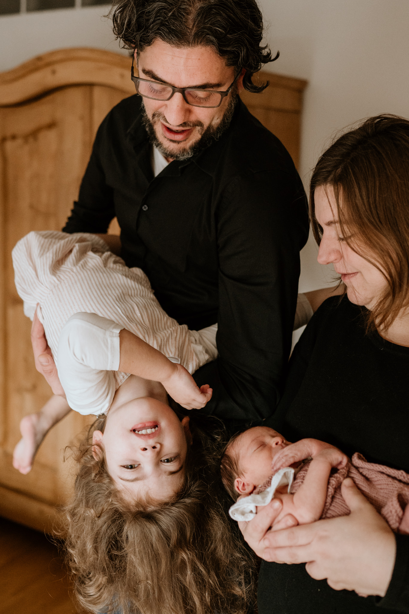Eltern halten Kleinkind kopfüber über das lachende Baby