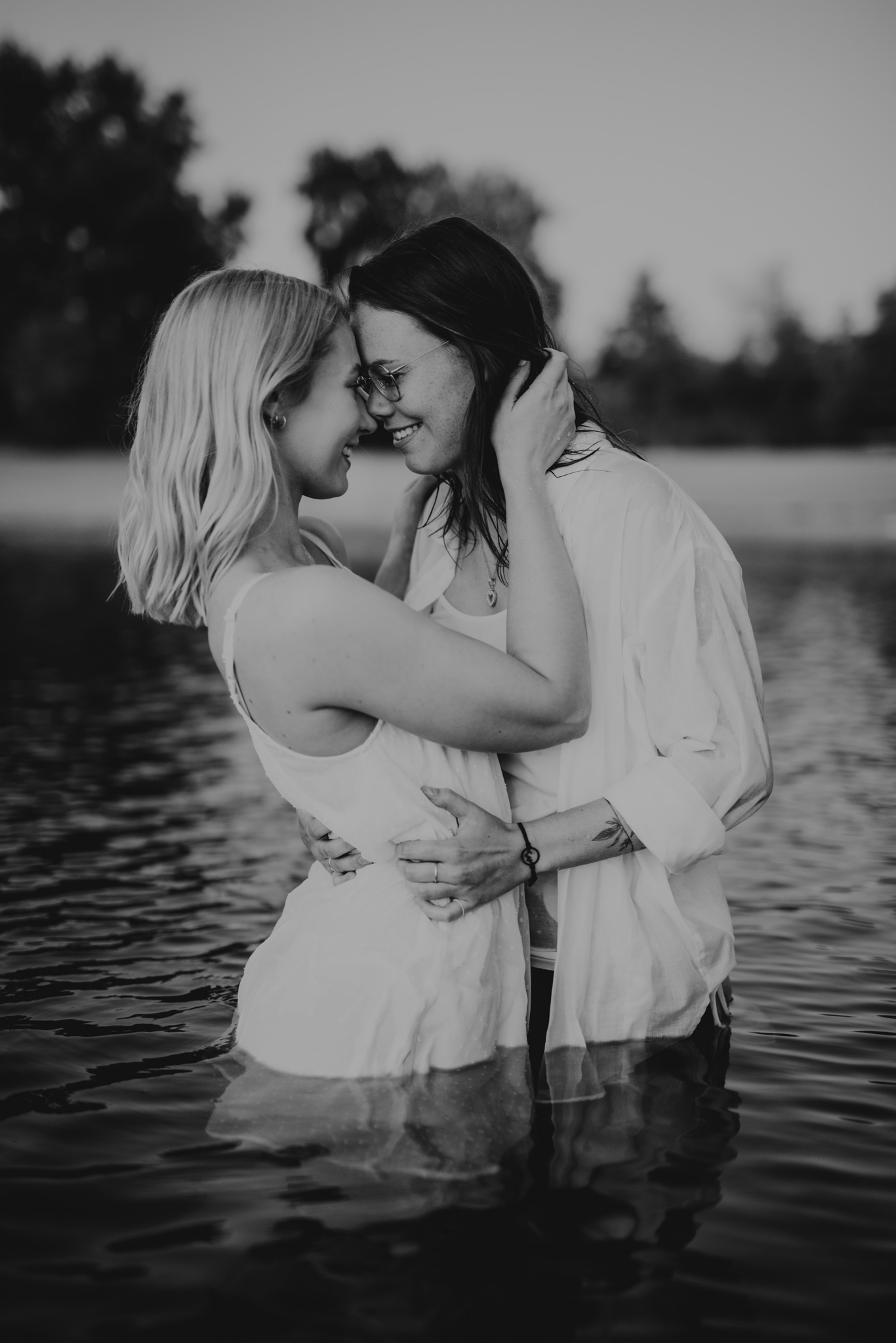Zwei Frauen umarmen sich eng im Wasser, Schwarzweißaufnahme