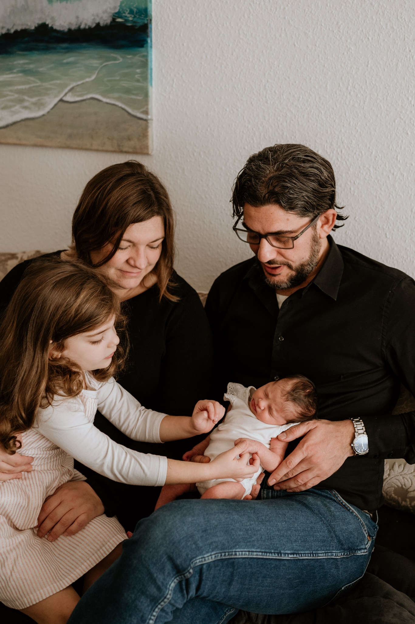 Familie betrachtet gemeinsam ihr neugeborenes Baby auf dem Sofa