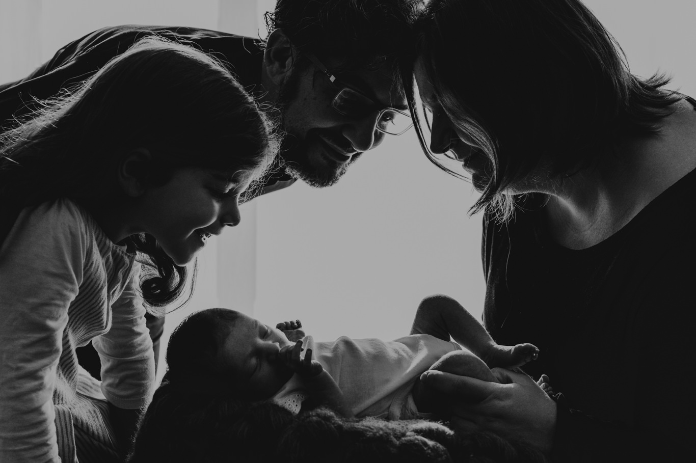 Schwarzweißaufnahme, Eltern beugen sich liebevoll über ihr Baby