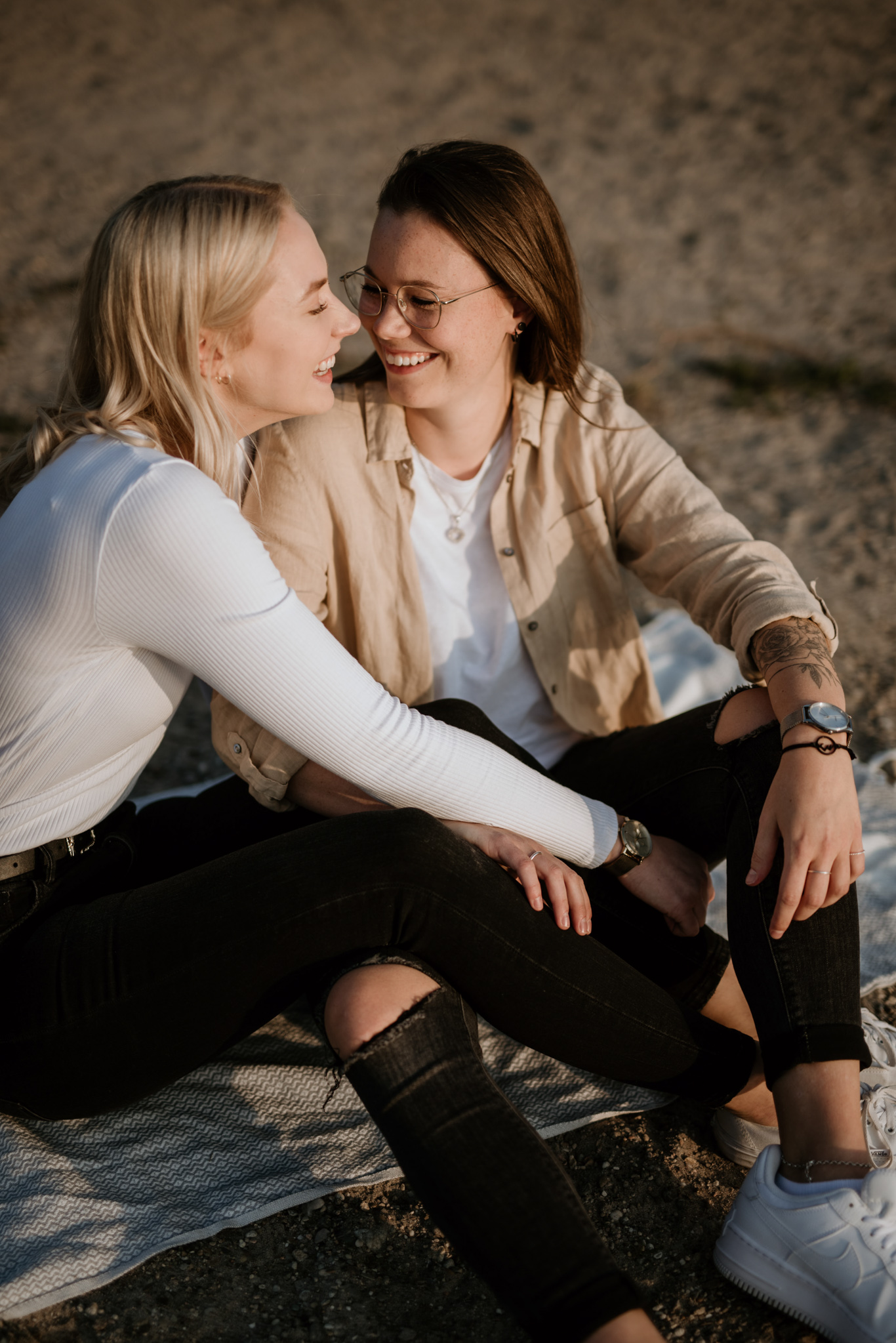 Paar sitzt lächelnd eng beieinander am Strand