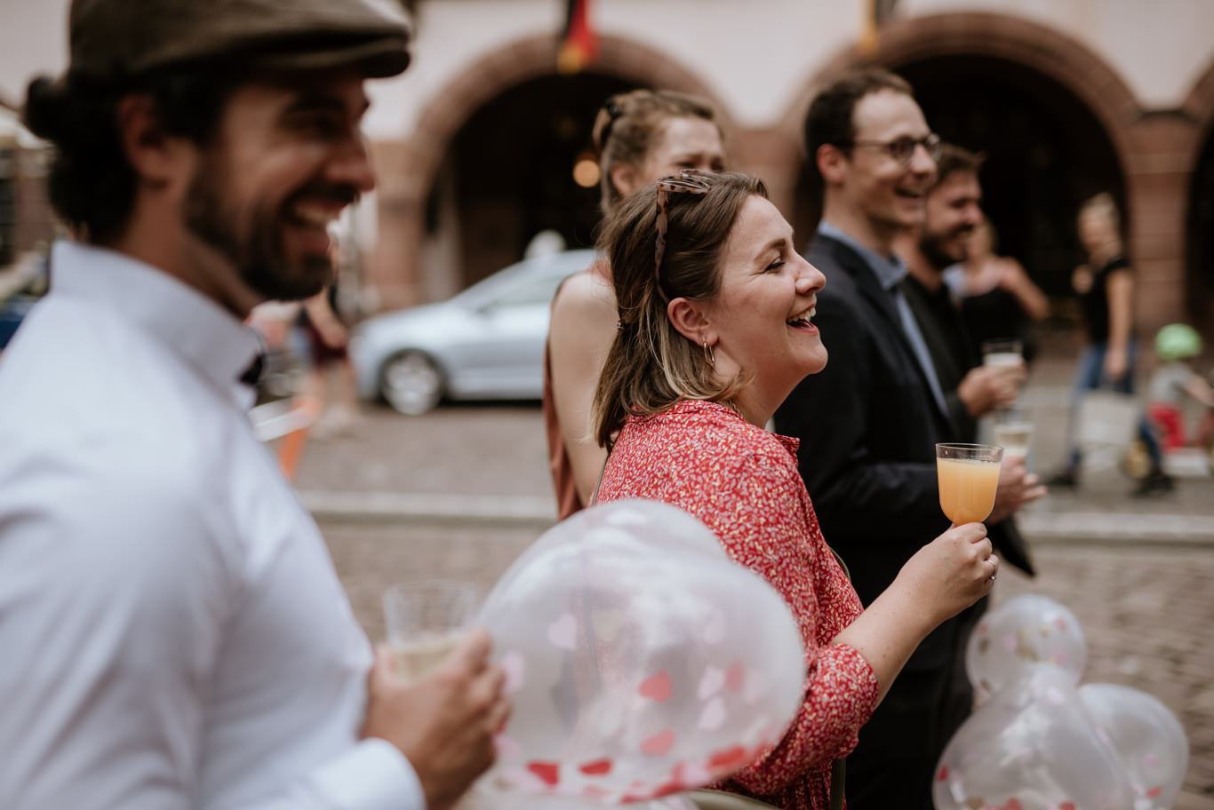Gäste lachen ausgelassen mit Sektgläsern auf der Straße