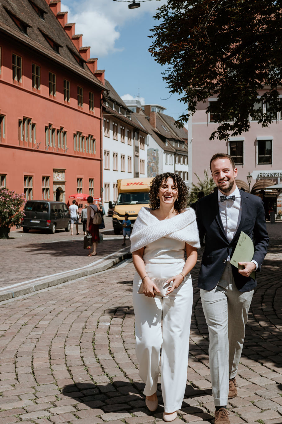 Brautpaar geht Hand in Hand über das Kopfsteinpflaster