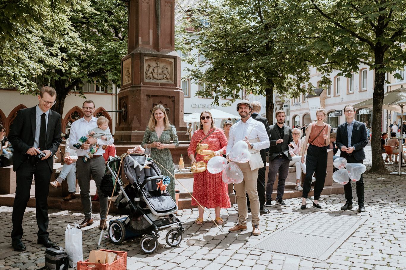 Gäste warten mit Kinderwagen am Brunnen auf dem Marktplatz