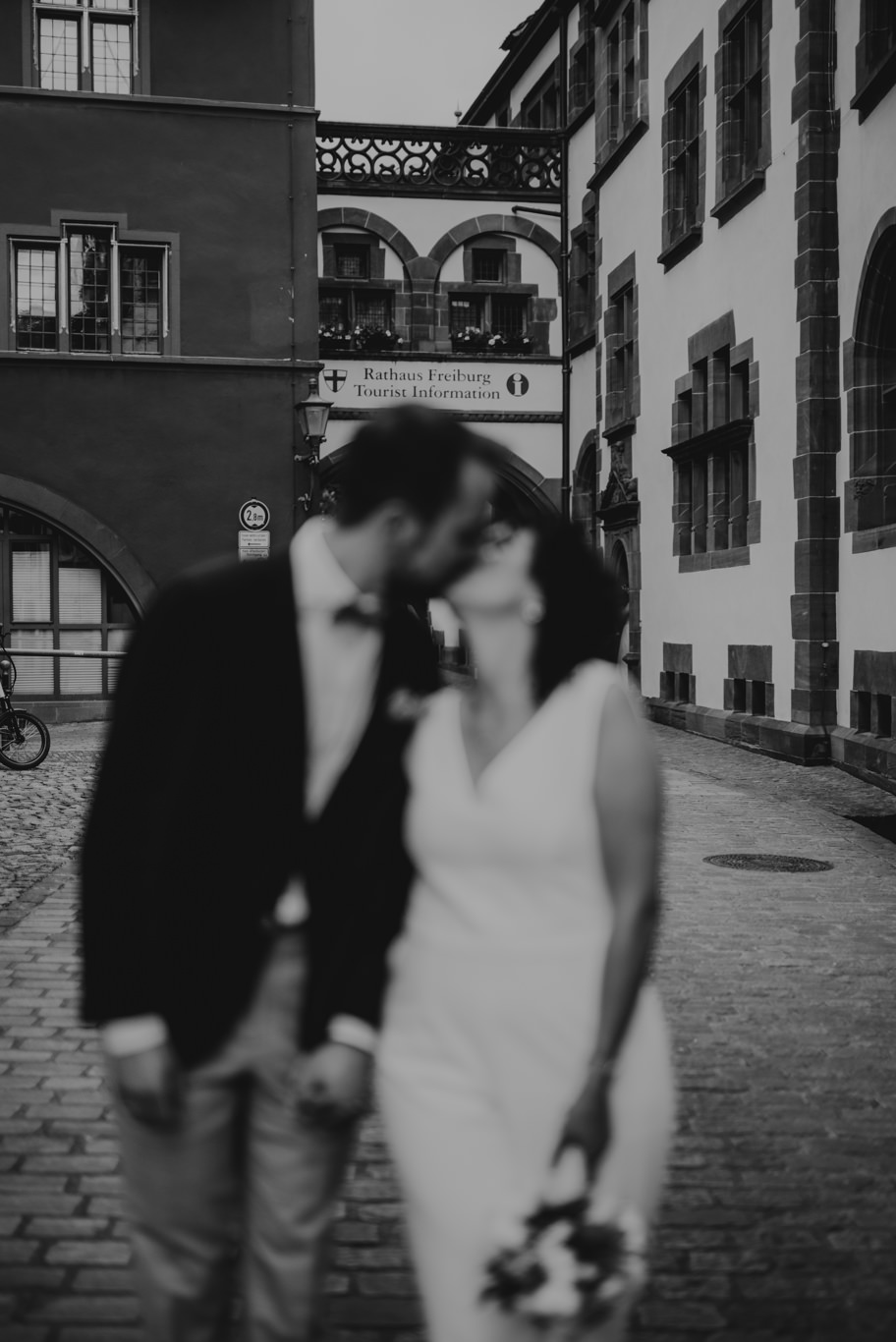 Bräutigam küsst Braut in der Altstadtgasse, Schwarzweißaufnahme