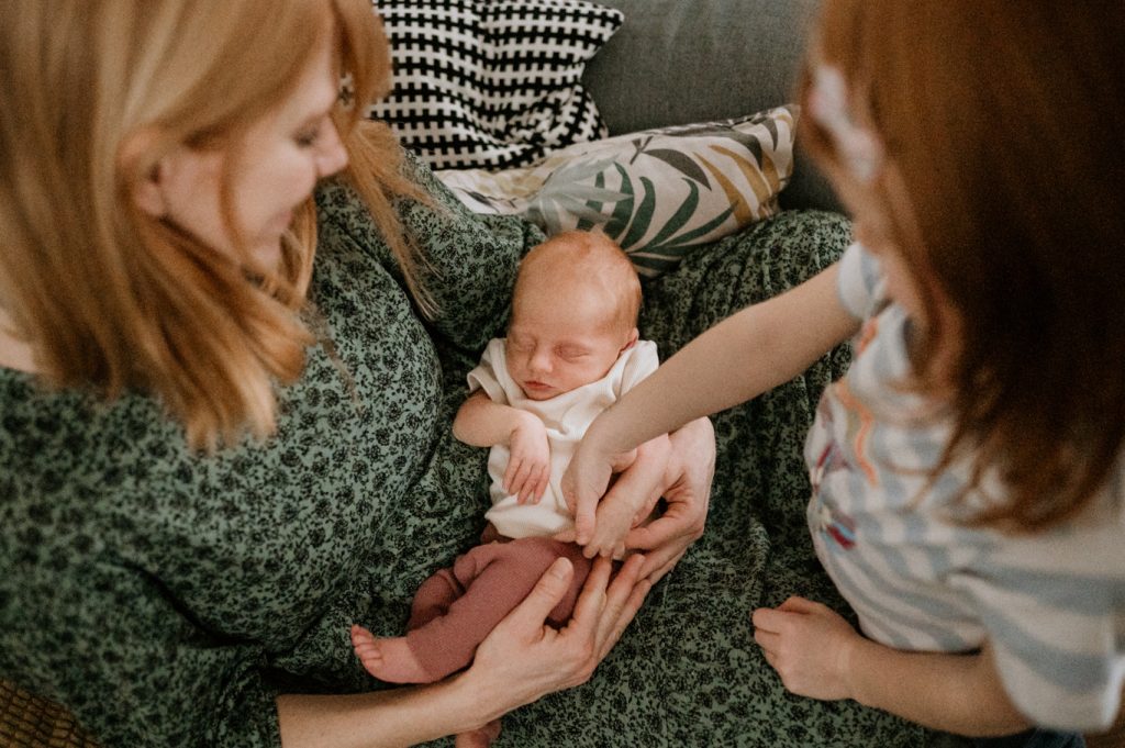 Mutter und Großmutter betrachten gemeinsam ein neugeborenes Baby