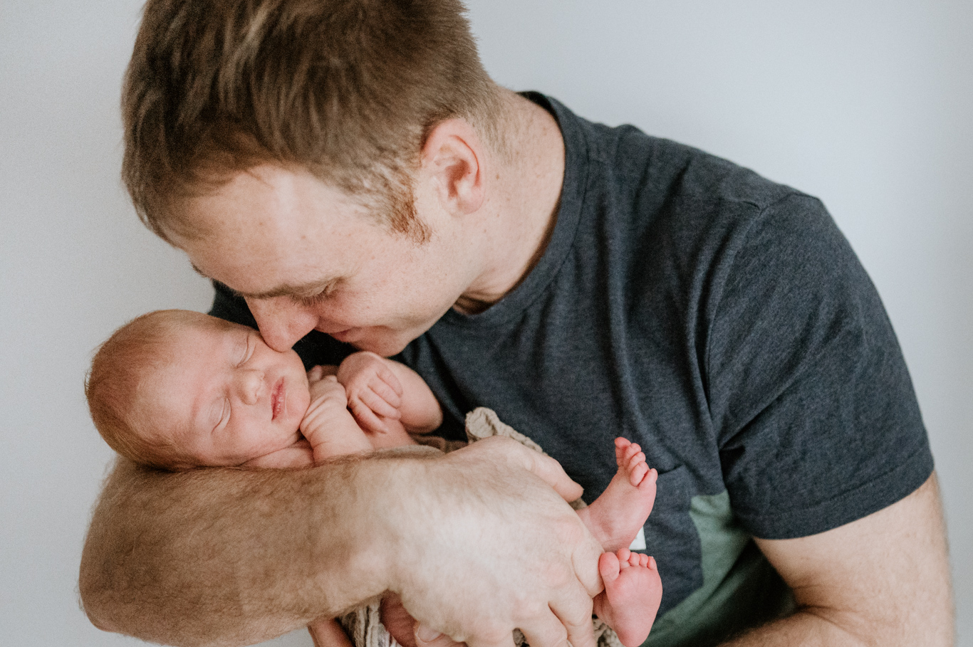 Vater küsst zärtlich sein schlafendes Baby auf der Schulter