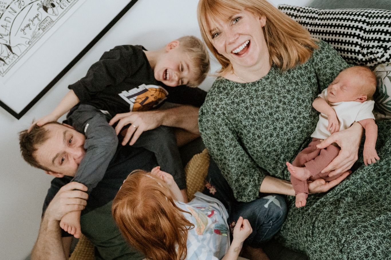 Vater liegt verspielt mit dem Sohn, Familie herzt das Baby