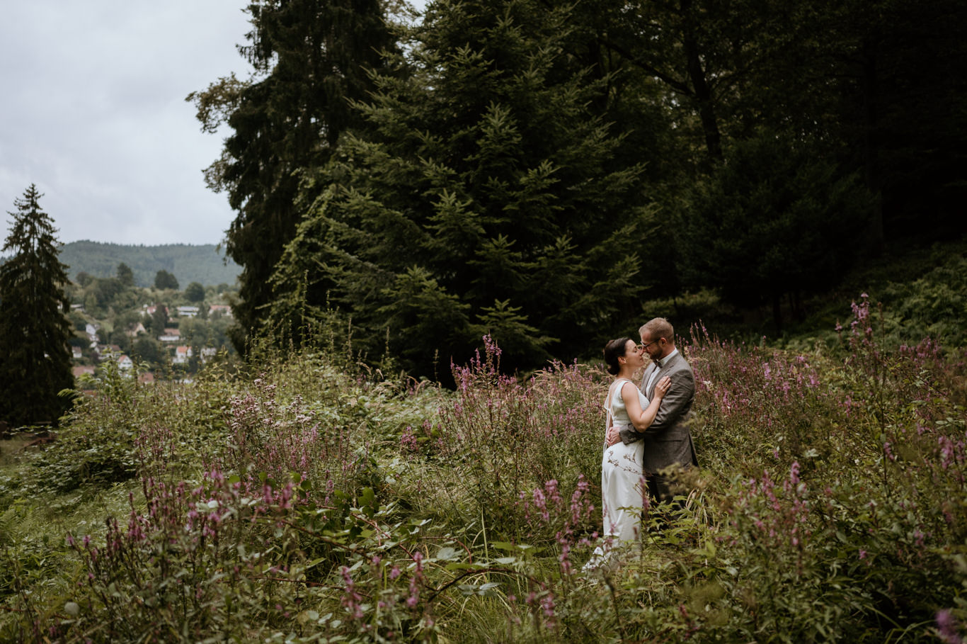 Brautpaar umarmt sich mit Blick auf Heidelberg im Tal