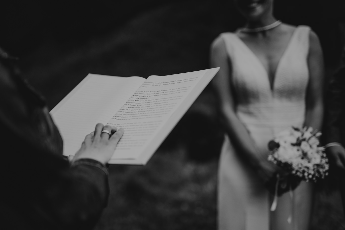 Traurednerin liest aus einem Buch neben der Braut, Schwarzweißaufnahme