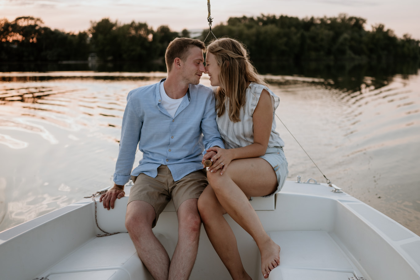 Paar sitzt lächelnd Stirn an Stirn auf dem Boot am See