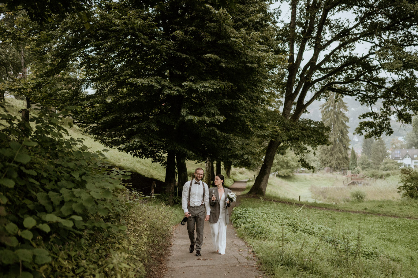 Brautpaar geht Hand in Hand einen Waldweg entlang