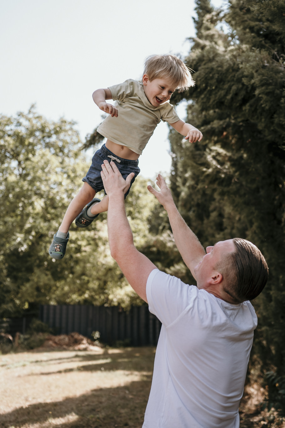 Vater wirft Jungen hoch in die Luft, Mutter schaut zu