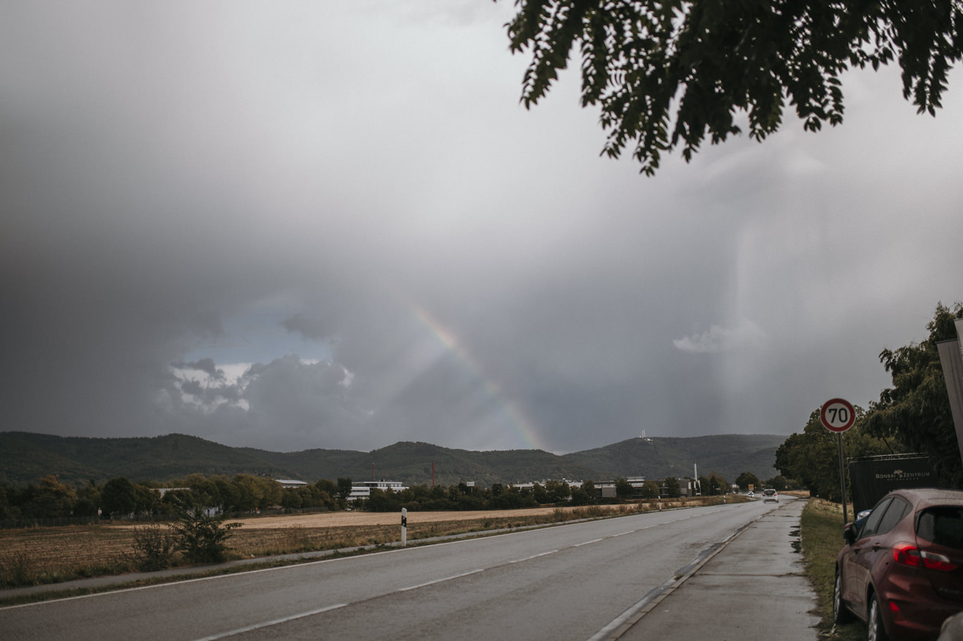 Regenbogen über einer Landstraße nach einem Sommerregen
