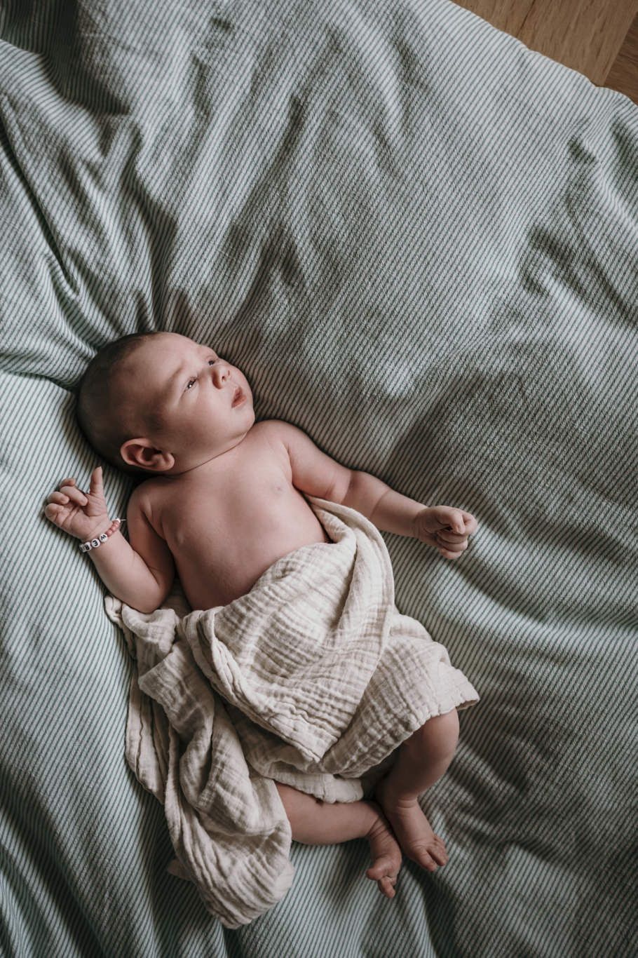 Neugeborenes liegt schlafend auf dem Bett, von oben fotografiert