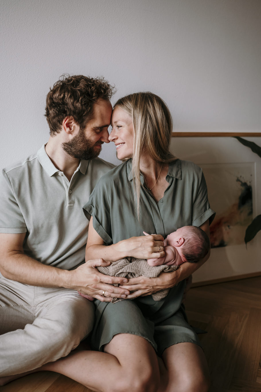 Eltern küssen sich, Vater hält das schlafende Baby im Arm