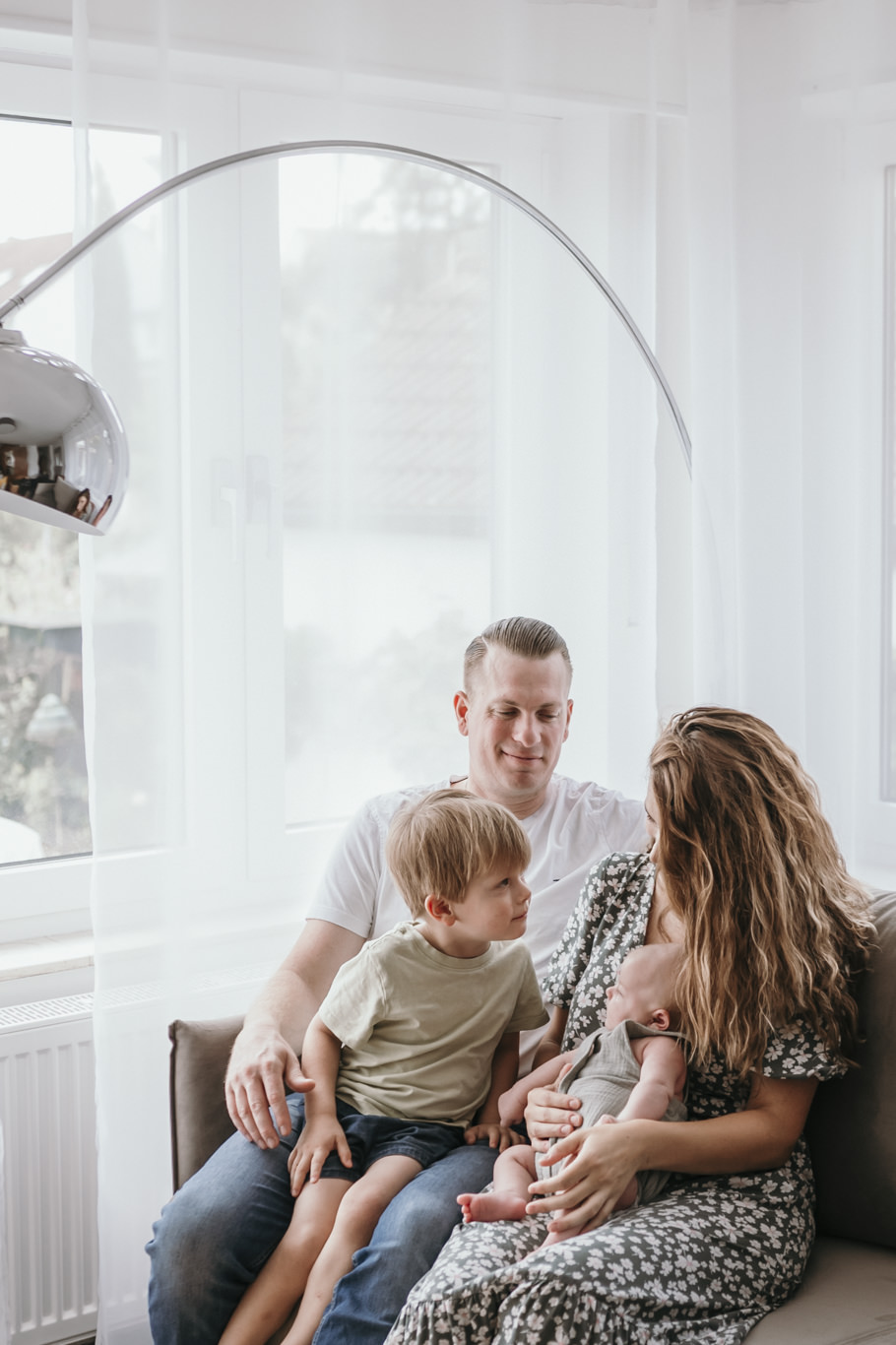 Familie sitzt entspannt mit zwei Kindern am Fenster