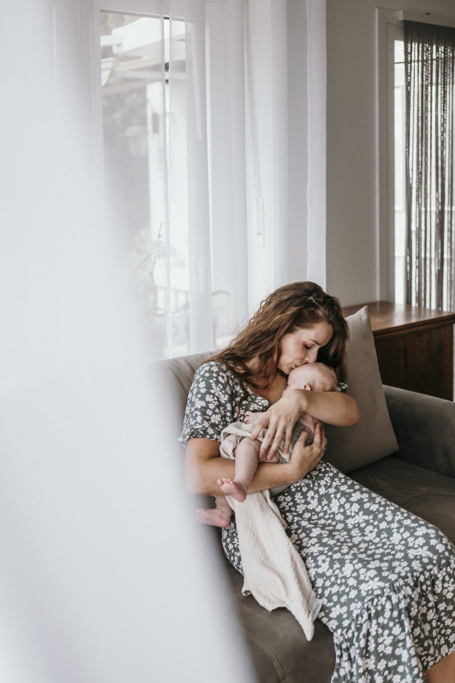 Mutter hält schlafendes Baby im Arm am Fenster