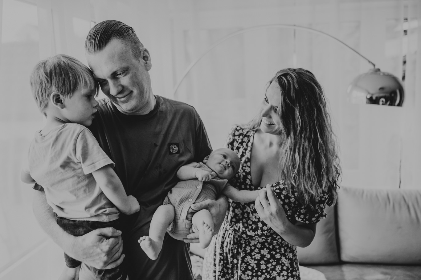Eltern und Kleinkind blicken lächelnd auf das Baby, Schwarzweißaufnahme