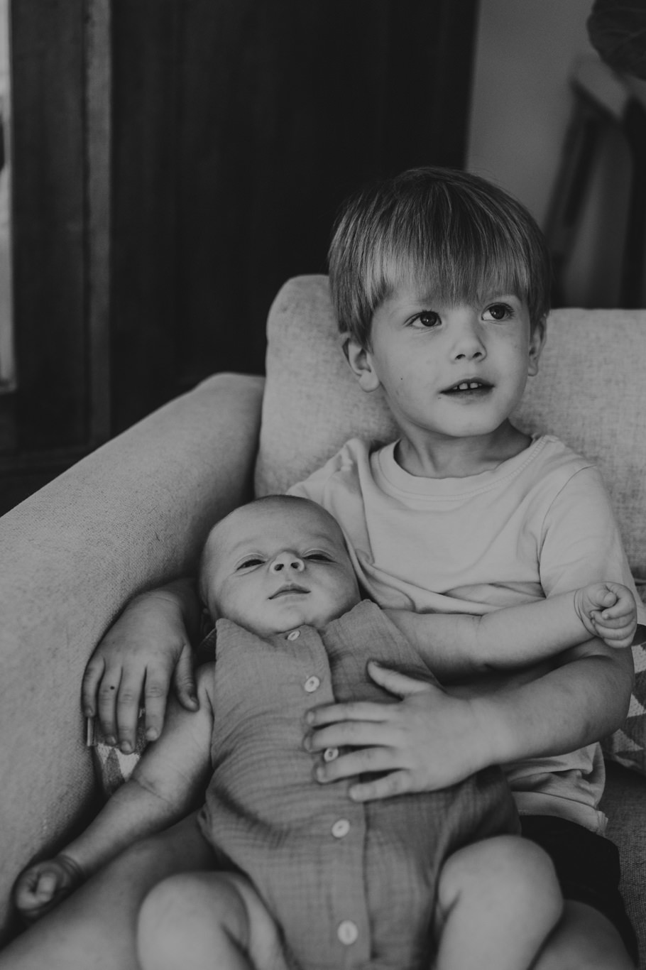 Schwarzweißaufnahme eines Jungen, der sein Geschwisterchen im Arm hält