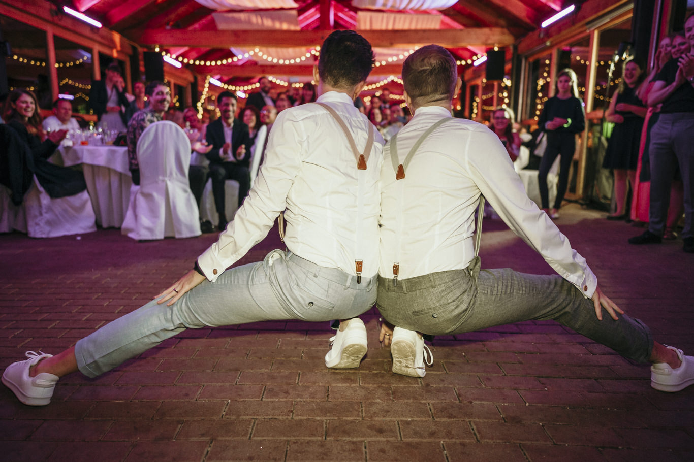 Zwei Bräutigame springen tanzend mit gespreizten Beinen auf der Tanzfläche
