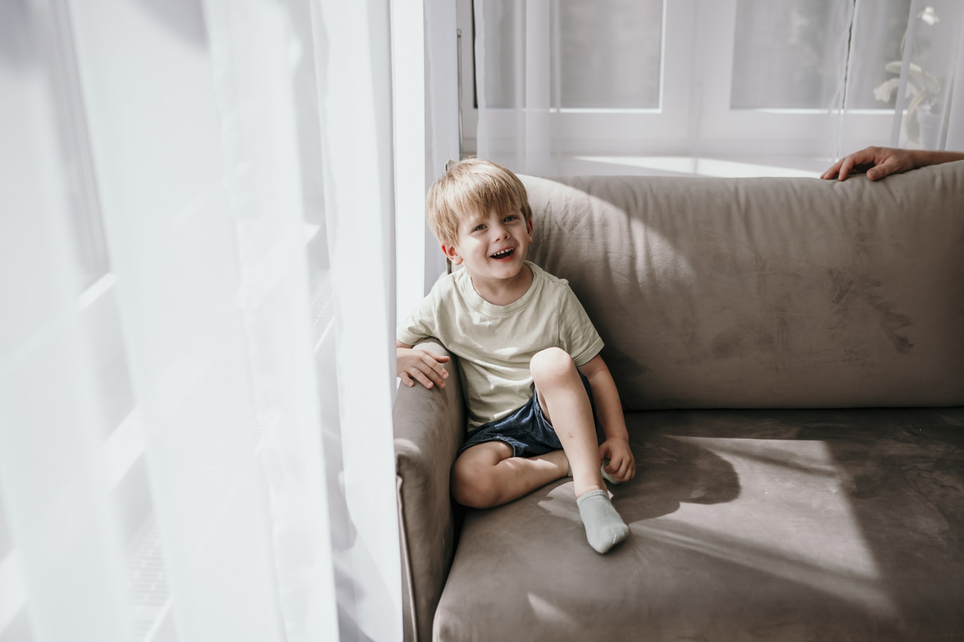 Kleinkind sitzt allein auf dem Sofa am Fenster