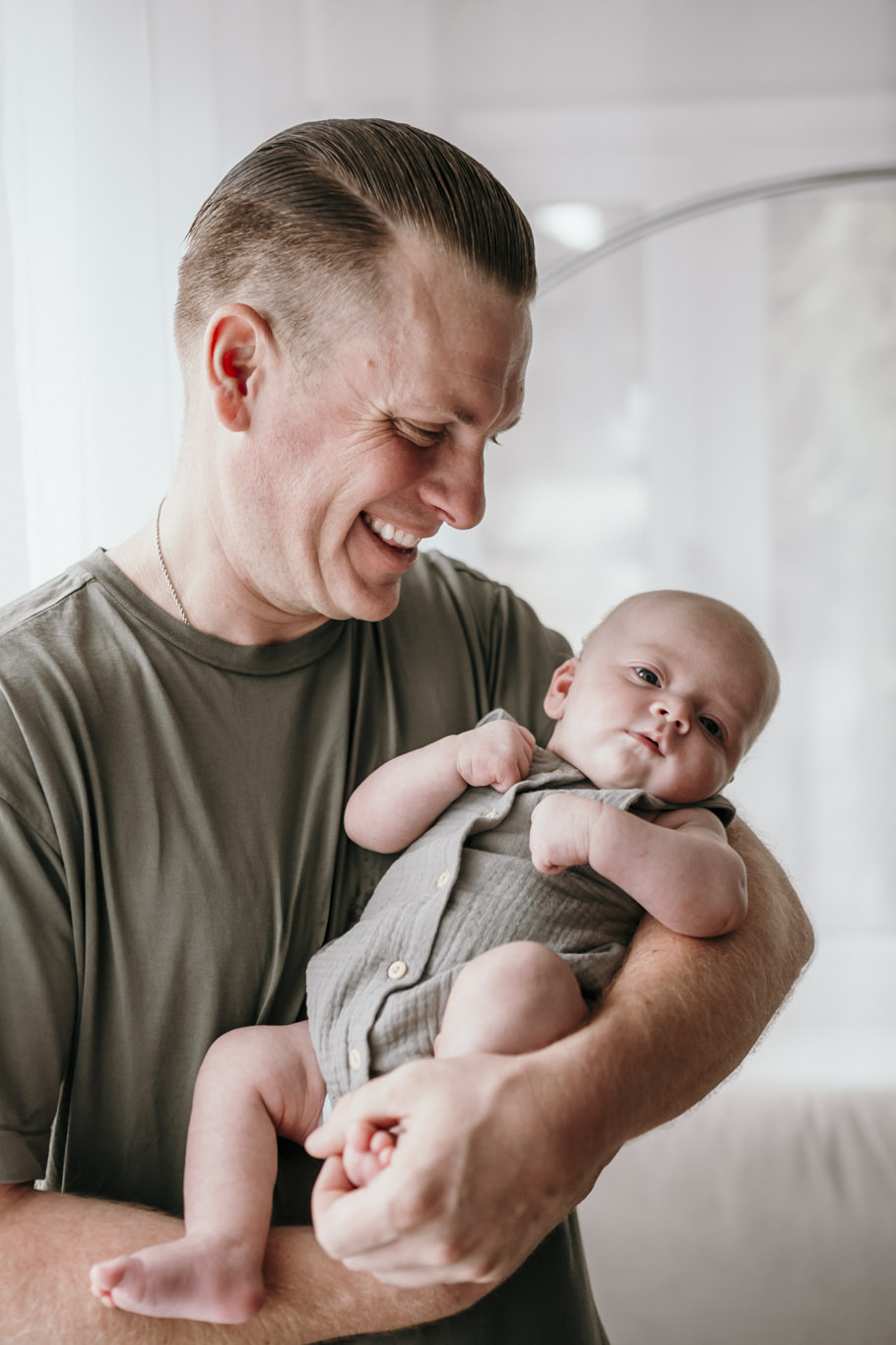 Vater hält lächelnd sein neugeborenes Baby im Arm