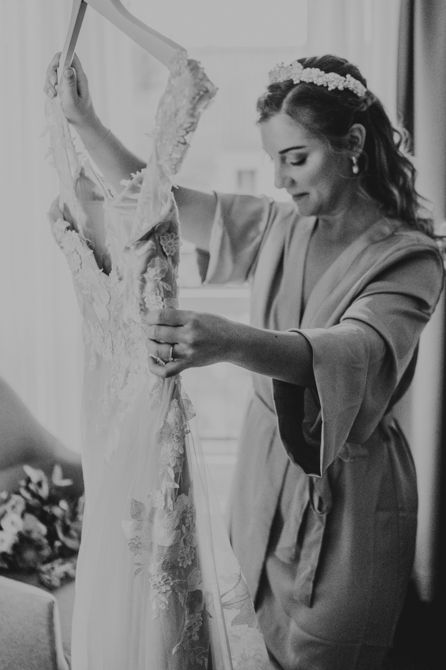 Braut betrachtet nachdenklich ihr Hochzeitskleid, Schwarzweißaufnahme