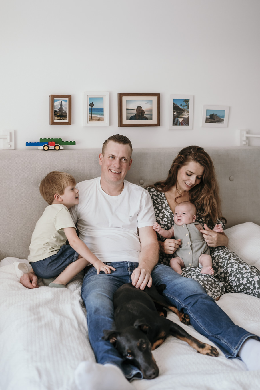 Familie liegt mit Hund und Kindern gemeinsam auf dem Bett