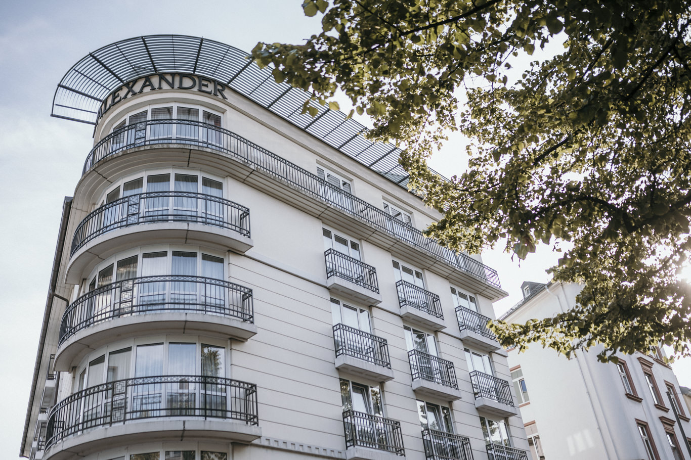 Fassade eines historischen Stadthauses mit Balkonen und Bäumen