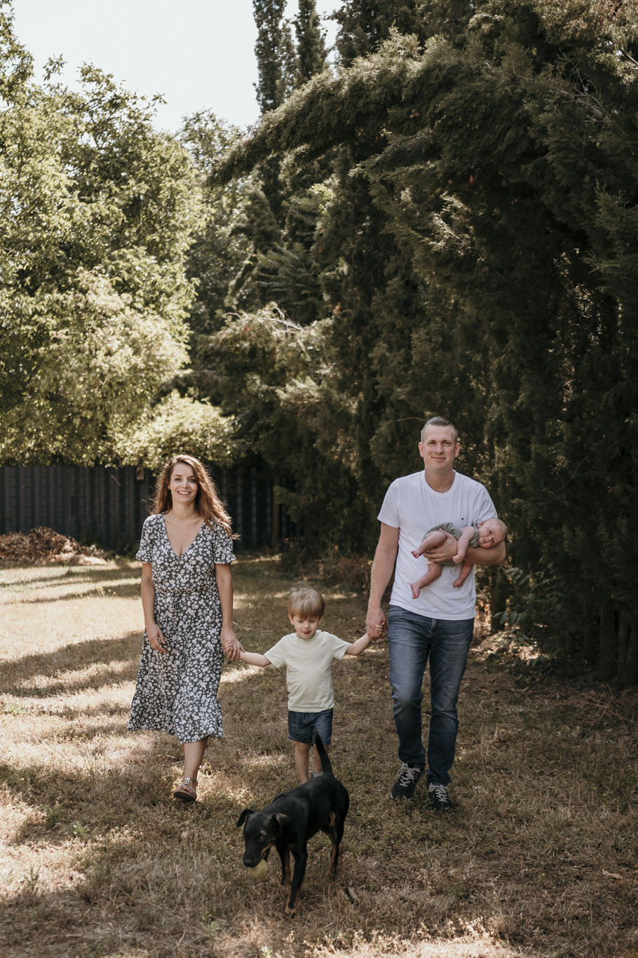 Familie geht mit Hund und Kindern durch den Garten