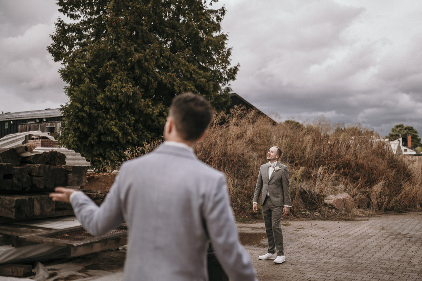 Bräutigam steht seinem Partner vor rustikaler Kulisse im Bonsai Zentrum gegenüber