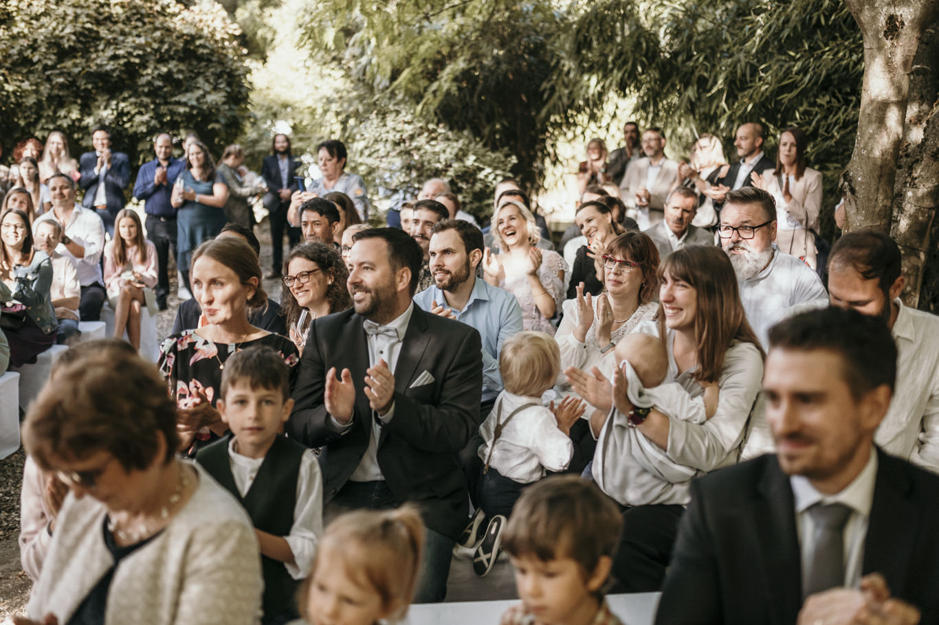 Gäste applaudieren sitzend während der Trauzeremonie im Freien