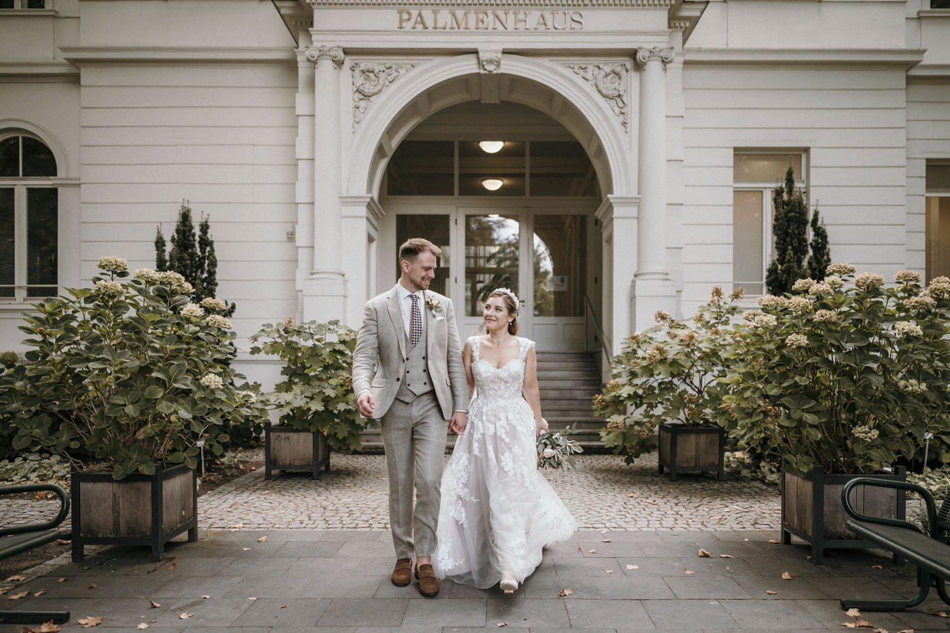 Brautpaar geht Hand in Hand vor dem Palmenhaus im Palmengarten