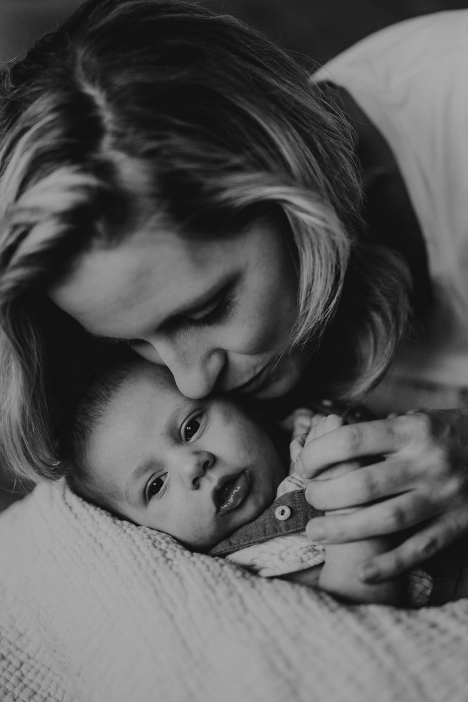 Schwarzweißaufnahme einer Mutter, die ihr Baby zärtlich küsst