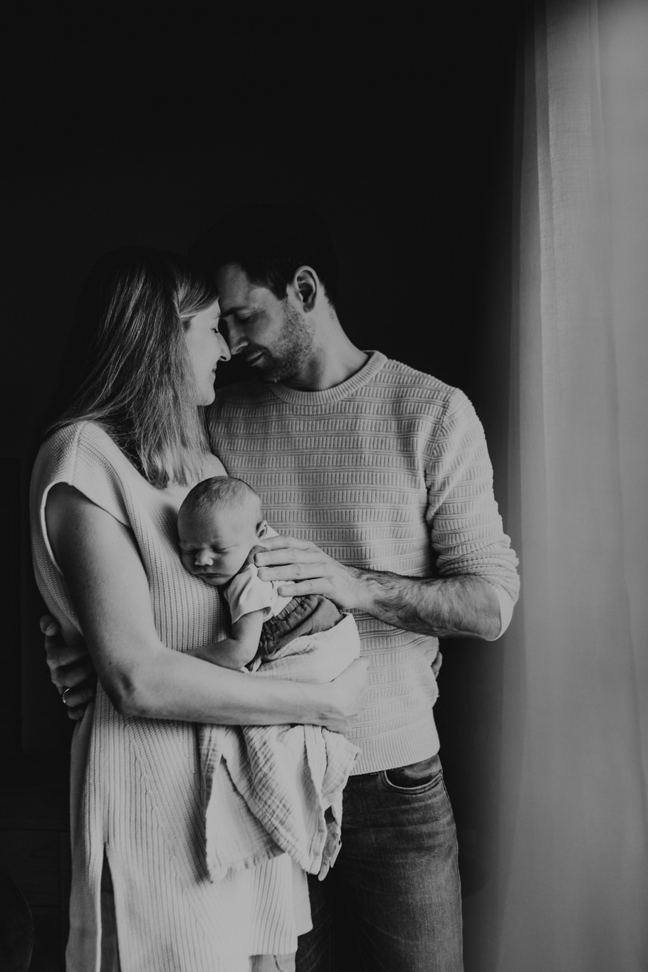 Schwarzweißaufnahme der Eltern, die ihr Baby im Arm halten