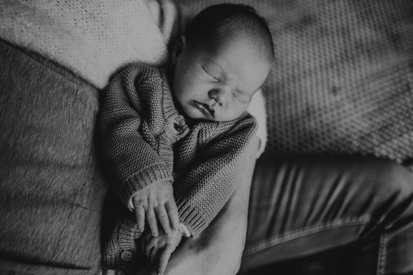 Schwarzweißaufnahme eines schlafenden Babys im gestrickten Body