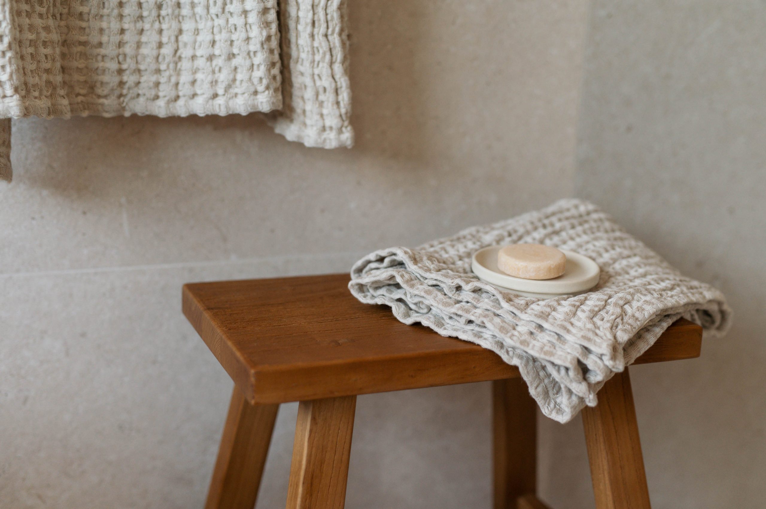 Holzhocker mit gefalteten Handtüchern und Seife im Badezimmer