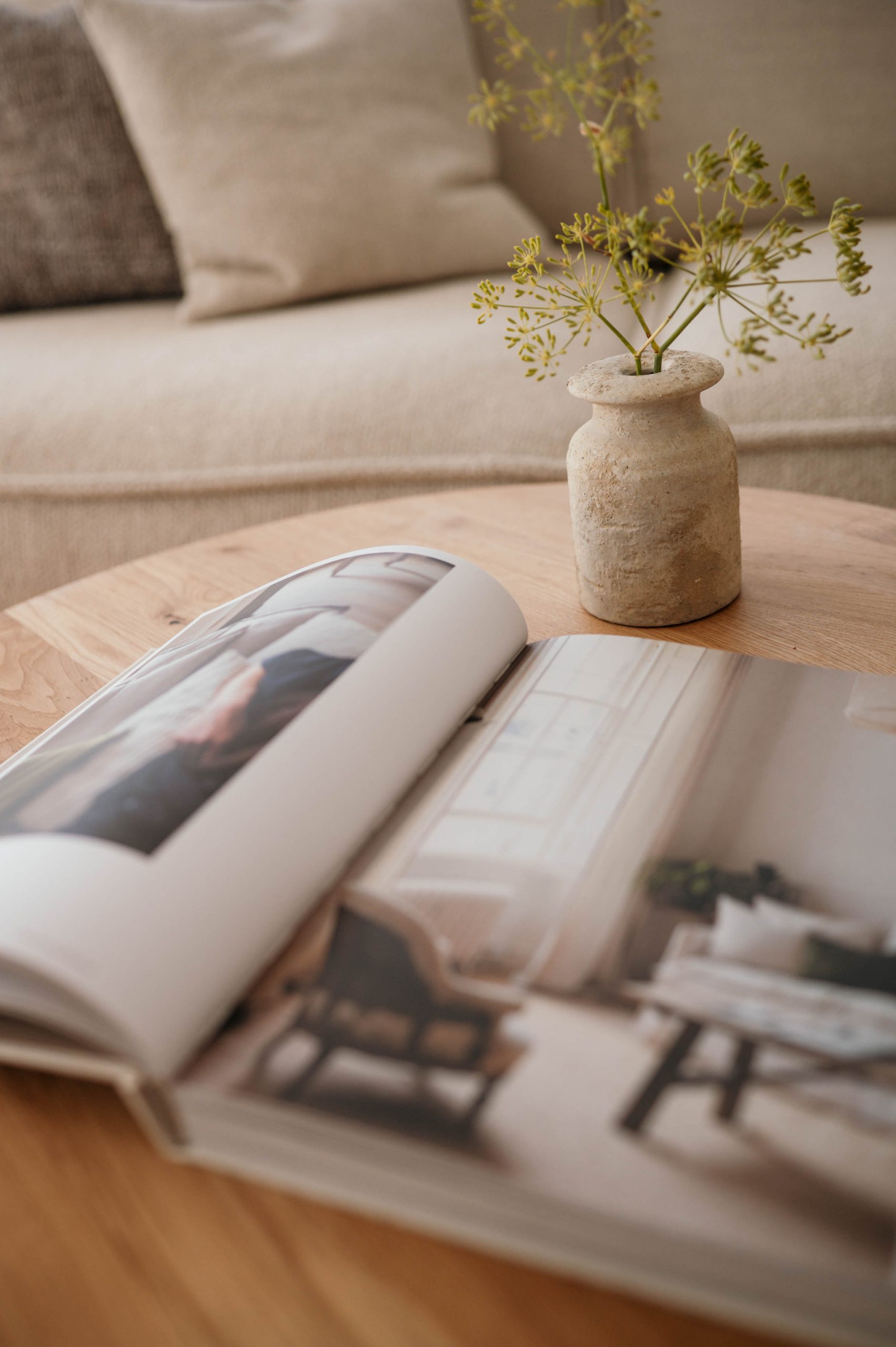 Aufgeschlagenes Magazin auf einem Couchtisch neben einer Vase