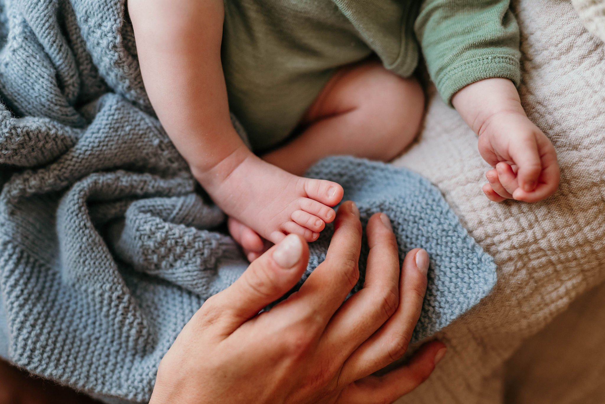 Zarte Babyfüßchen und Händchen in einer weichen blauen Decke