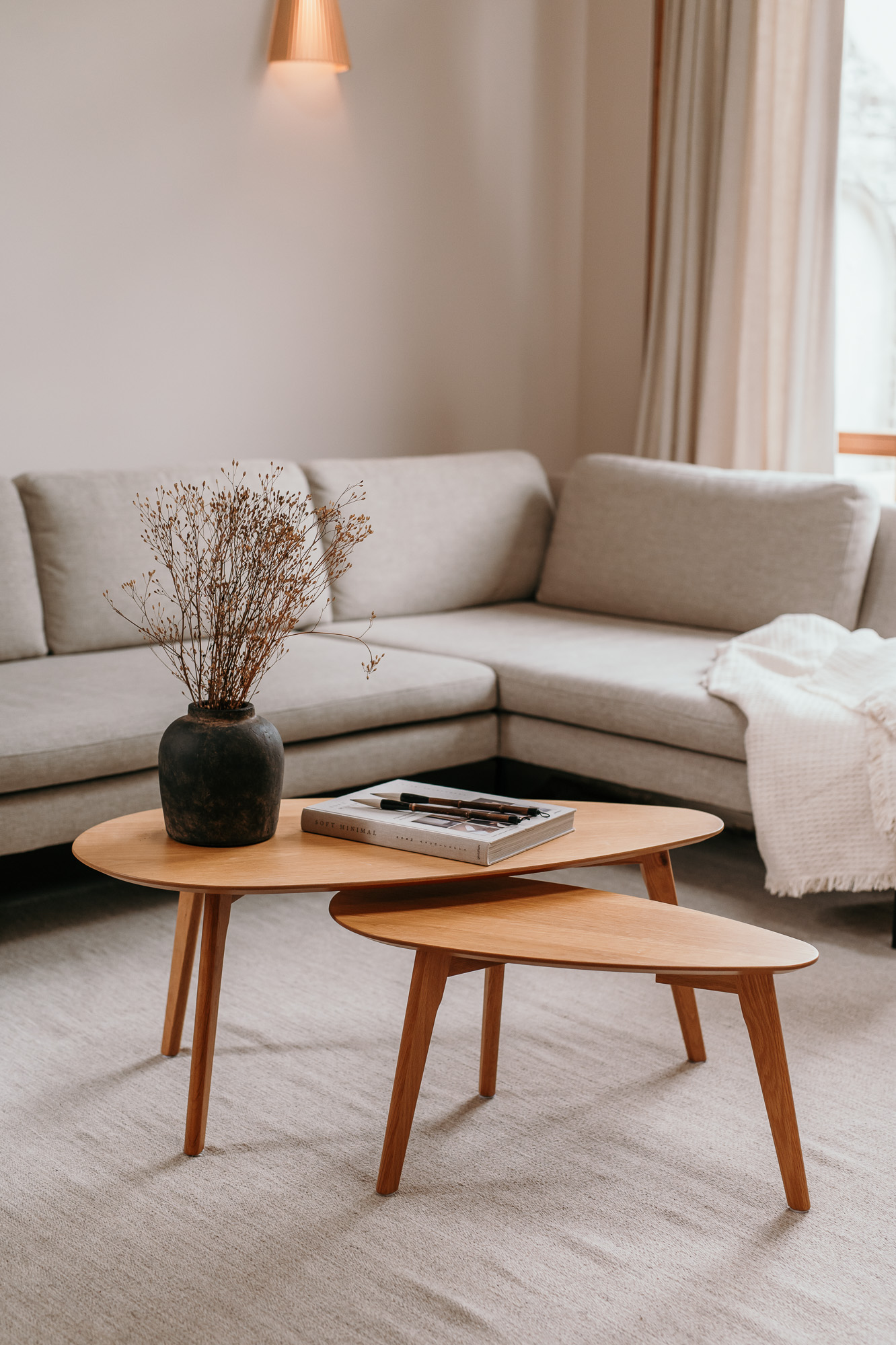 Runde Holztische vor einem hellen Sofa im Wohnzimmer