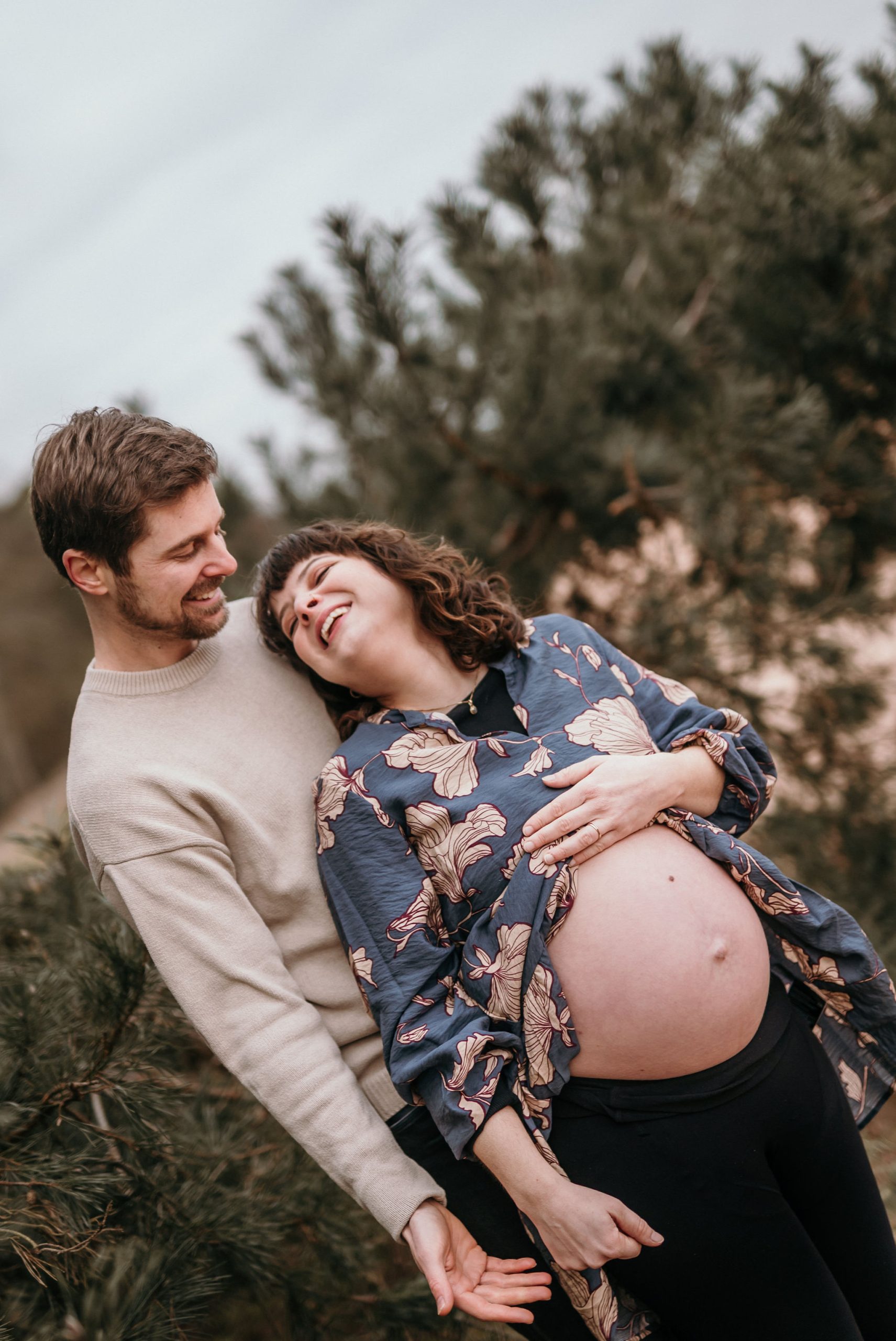 Schwangere Frau mit Partner lachend bei Babybauchshooting in der Pfalz